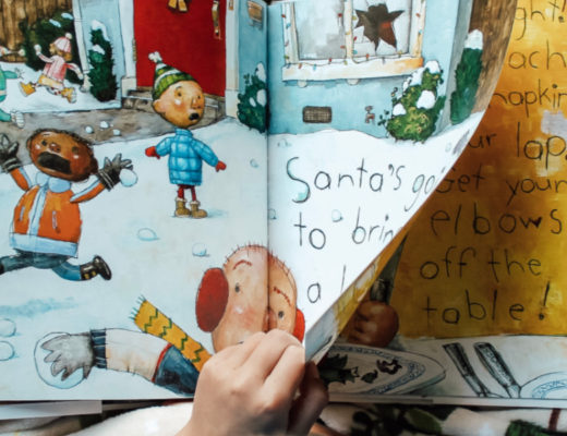 Child's hand turning page in Christmas book