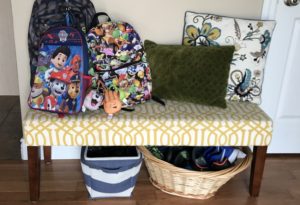 organized kids' shoes in a basket in entryway 