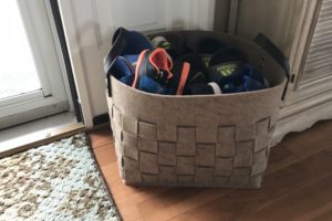organized kids's shoes in a basket by front door