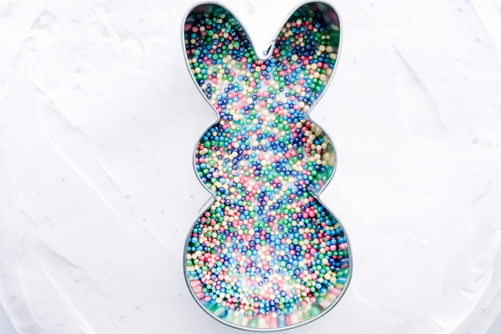 Sprinkles inside bunny cookie cutter on iced cake
