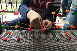 child's hand making a jelly bean toothpick building