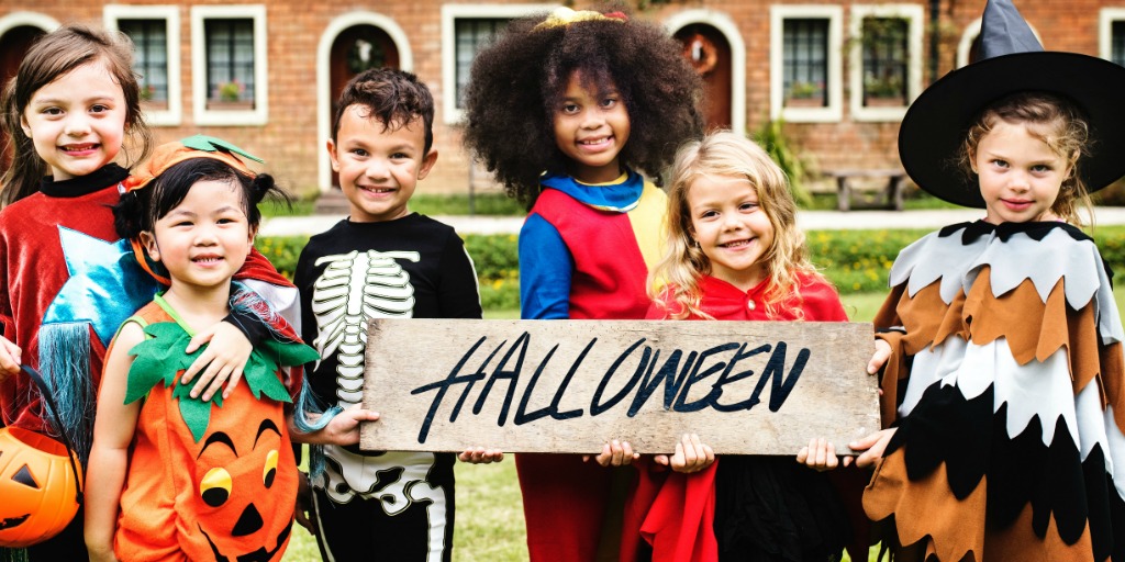 Children in costumes holding a Halloween sign