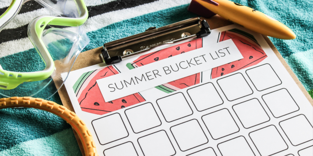 Summer Bucket List printable on clipboard on a beach towel with swim toys