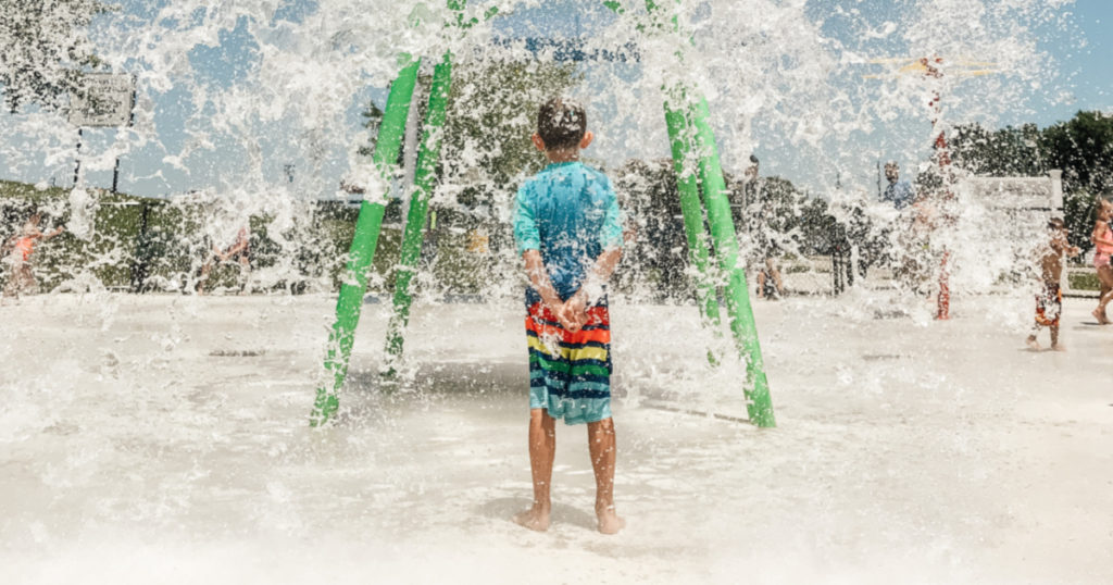child standing under water spout